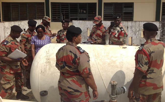 ACFO Frances Roskson (middle) and personnel of the GNFS examining a large size LPG installation outside the kitchen of Tema Senior High School
